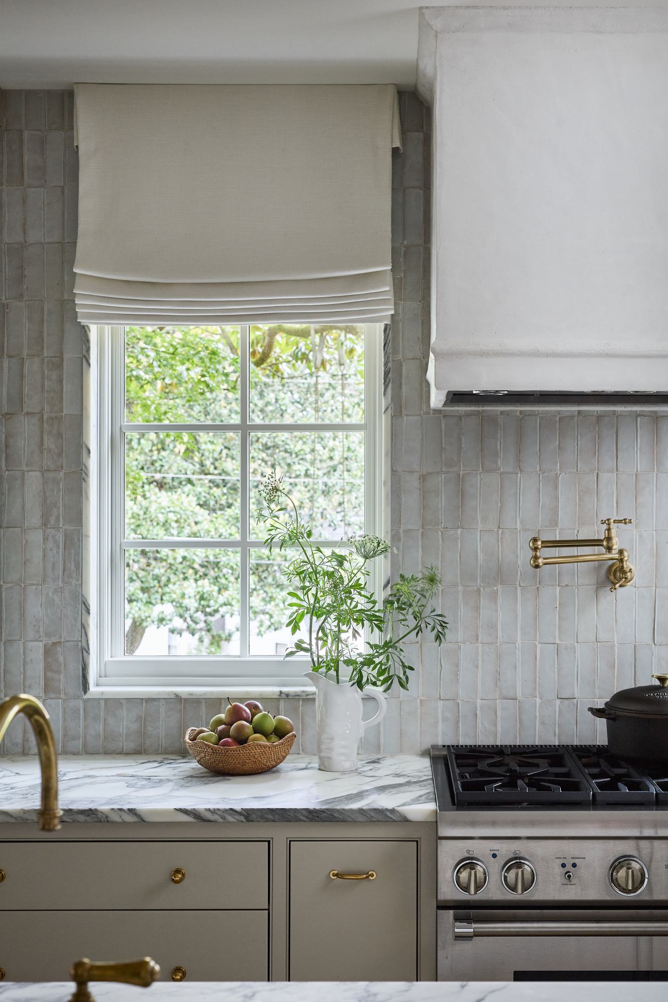 Kitchen window with handmade tile backsplash, marble counter, and a bowl of pears