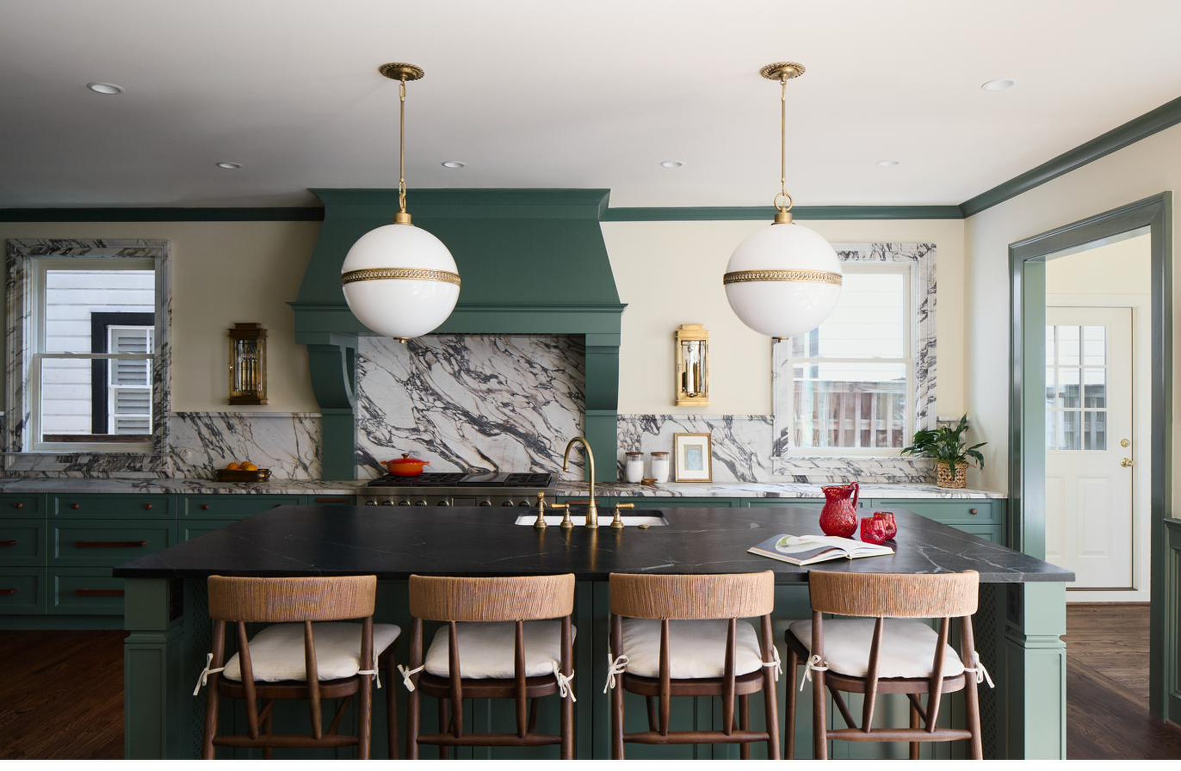 Sage green custom kitchen with marble slab backsplash, soapstone island, and brass globe pendant lights