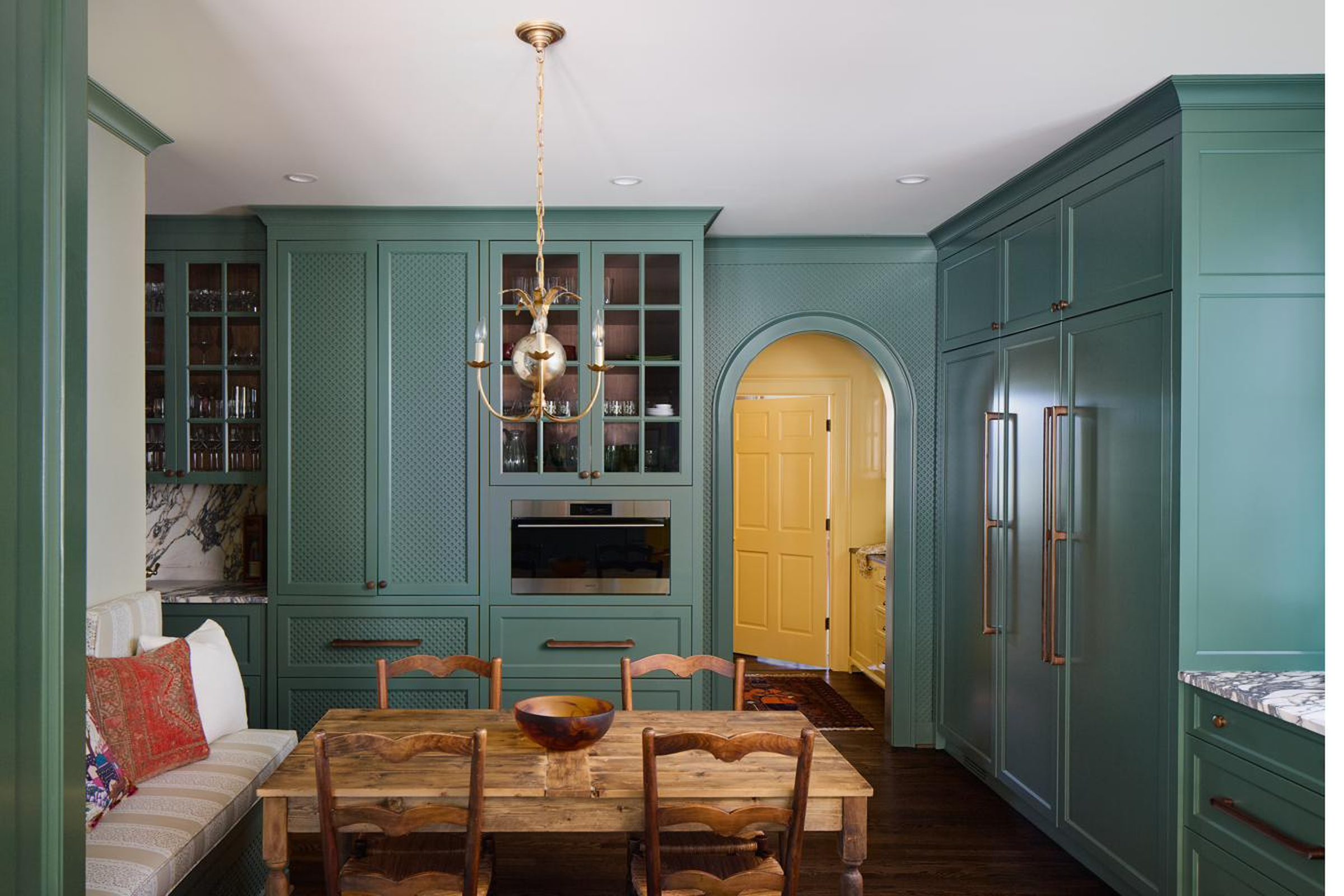 Green dining nook with reclaimed wood table and built-in bench