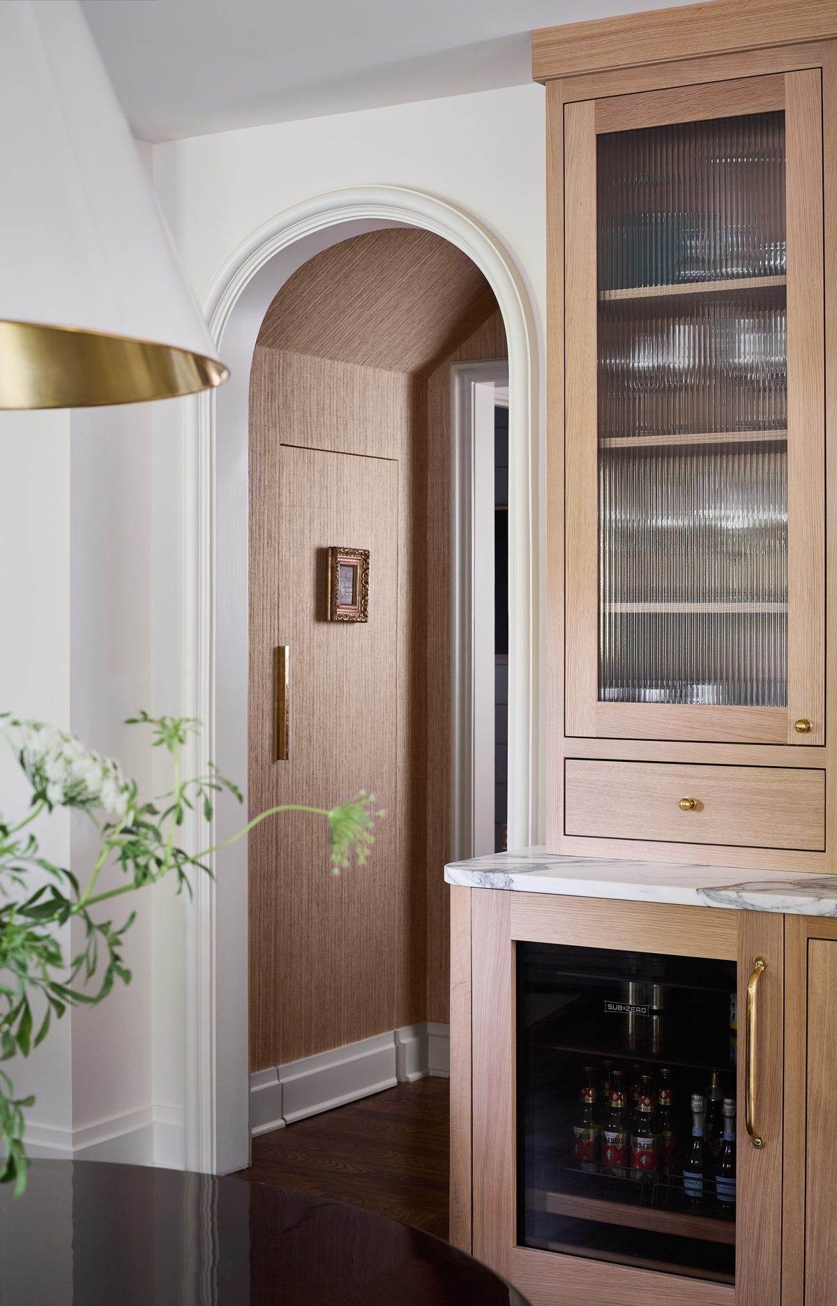 Arched bar nook with reeded glass cabinetry and brass hardware