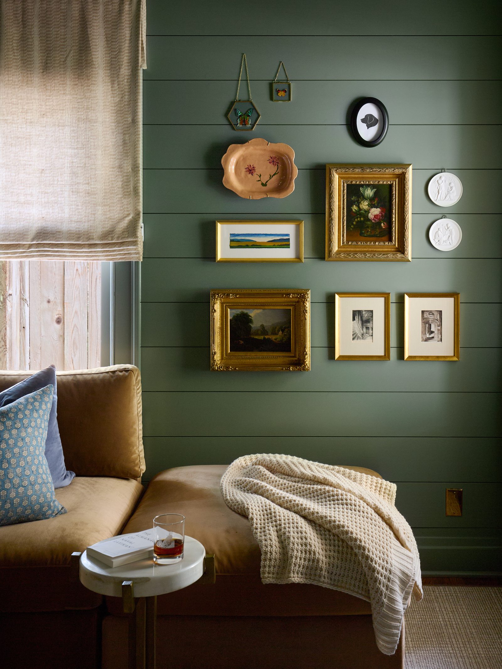 Moody green den with velvet sectional and curated gallery wall