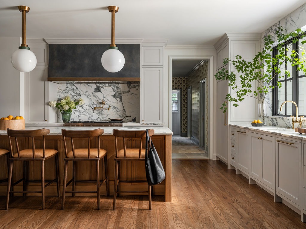 Kitchen with brass globe pendant lights, marble slab backsplash, and oak island