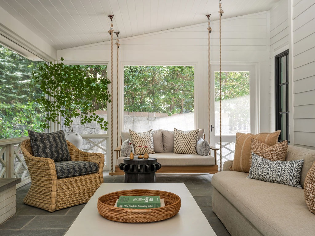 Screened sunporch with a hanging daybed swing and woven armchair
