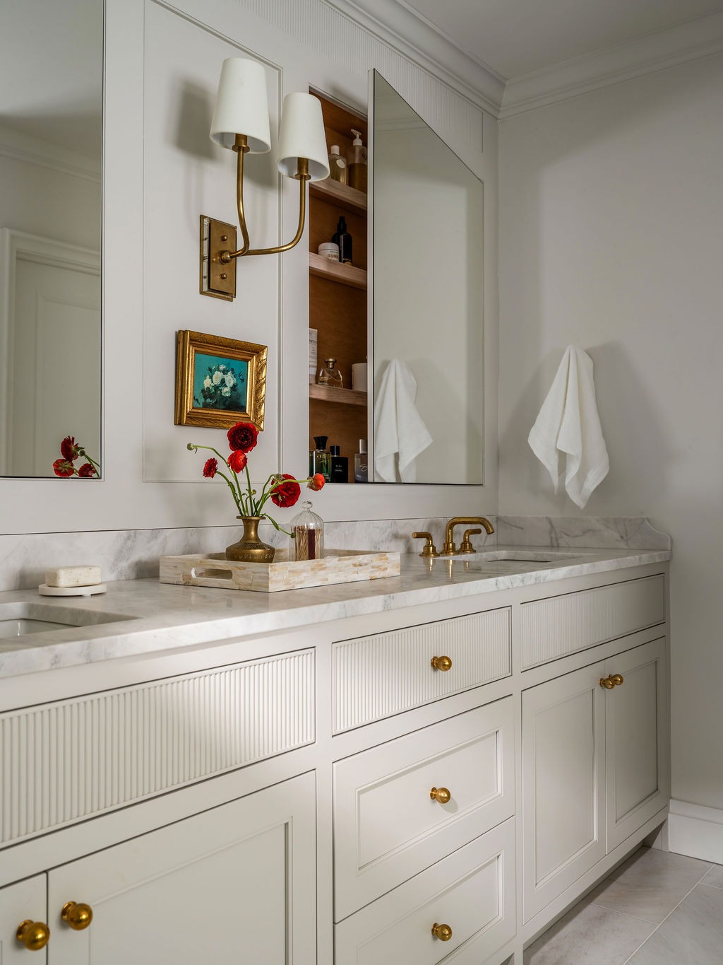Primary bathroom double vanity with brass sconces and marble countertops