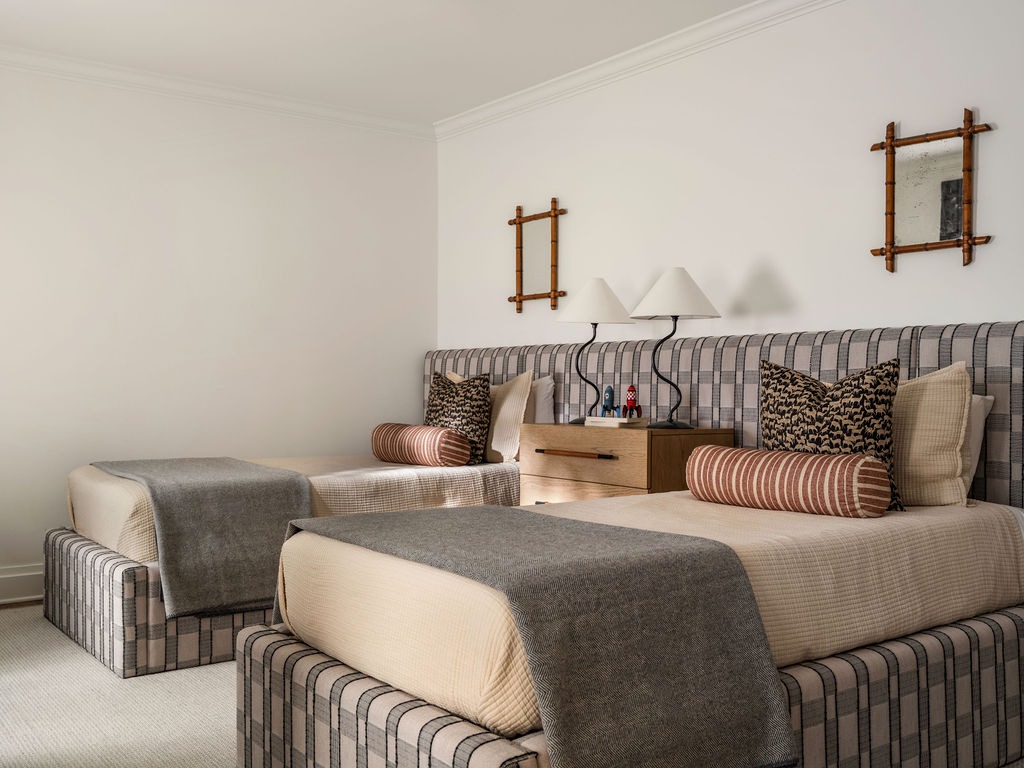 Twin guest bedroom with striped upholstered beds and bamboo-frame mirrors